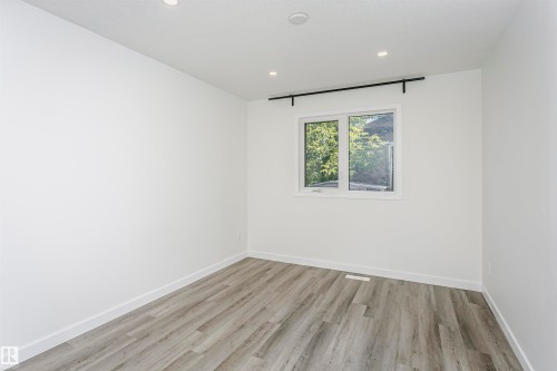 Room featuring white walls, recessed ceiling lighting, a window with white trim, and wood-finish flooring - 17716 84 Avenue, Edmonton, AB 