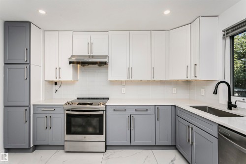Modern kitchen featuring white and gray shaker-style cabinetry, white countertops, a stainless steel range, and a black gooseneck faucet over a stainless steel sink - 17716 84 Avenue, Edmonton, AB 