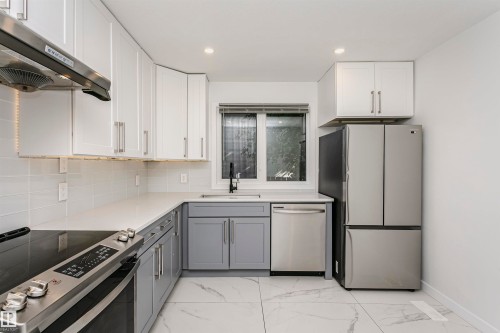 Modern kitchen featuring two-tone cabinetry, stainless steel appliances, white countertops, and a subway tile backsplash - 17716 84 Avenue, Edmonton, AB 