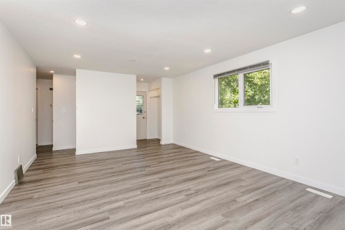 Spacious room featuring wood-finish flooring, recessed lighting, and a double window with blinds - 17716 84 Avenue, Edmonton, AB 