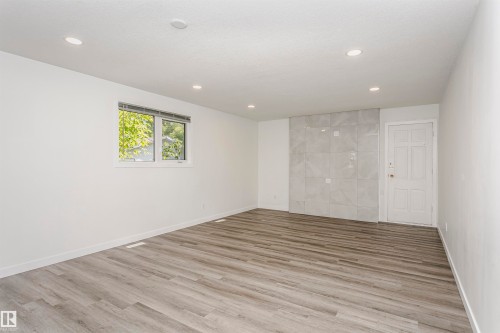 Spacious room with wood-finish flooring, recessed lighting, and a window with horizontal blinds - 17716 84 Avenue, Edmonton, AB 