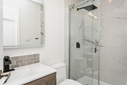 Contemporary bathroom featuring a glass-enclosed shower with a black rain showerhead and white veined tile surround - 17716 84 Avenue, Edmonton, AB 