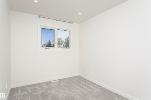 Neutral-toned room featuring a double-pane window, recessed lighting, light gray carpeting, and white baseboards - 17716 84 Avenue, Edmonton, AB 