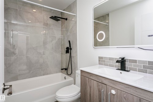 Bathroom featuring a modern vanity with a white countertop and rectangular sink, complemented by a matte black faucet - 17716 84 Avenue, Edmonton, AB 