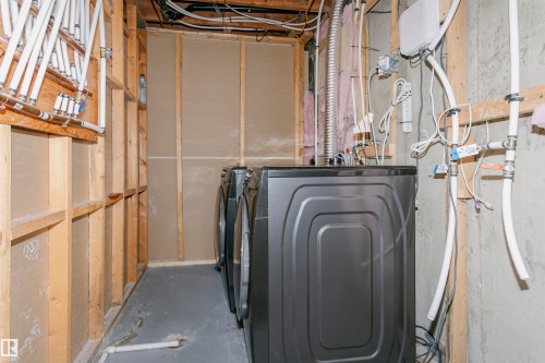 Dedicated laundry area featuring a washer and dryer, exposed wood framing, and visible utility connections - 17716 84 Avenue, Edmonton, AB 