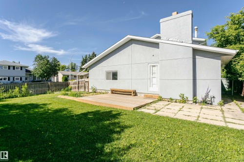 Expansive backyard featuring a lush lawn, wooden deck, and concrete patio - 17716 84 Avenue, Edmonton, AB 