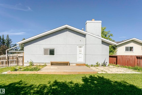 Rear exterior showcasing a wood deck, stucco siding, and a white entry door - 17716 84 Avenue, Edmonton, AB 