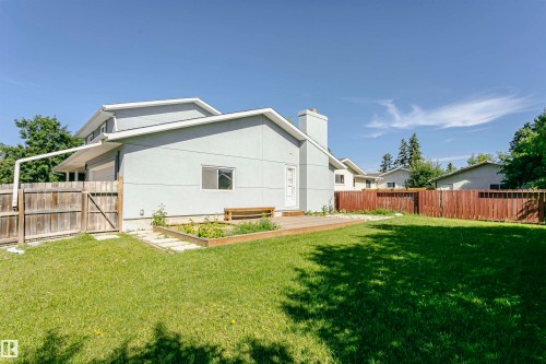 Expansive green lawn with a wooden perimeter fence, raised garden bed, and a wooden deck - 17716 84 Avenue, Edmonton, AB 