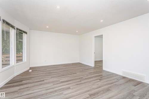 Spacious interior room featuring wood-finish flooring, white walls, and recessed lighting - 17716 84 Avenue, Edmonton, AB 