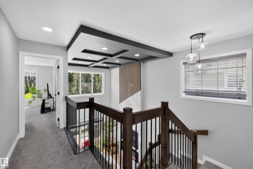Upper landing featuring a coffered ceiling with recessed lighting, dark wood railing with black metal spindles, and a multi-globe pendant light - 1573 Esaiw Place, Edmonton, AB 