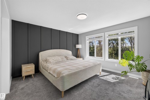 Bedroom featuring a dark paneled accent wall, two large windows with white trim, gray wall paint, gray carpeting, and a flush-mount ceiling light - 1573 Esaiw Place, Edmonton, AB 