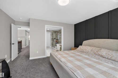Bedroom featuring plush gray carpeting and a prominent dark accent wall with vertical paneling - 1573 Esaiw Place, Edmonton, AB 