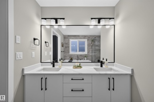 Dual vanity with white cabinetry and integrated sinks, complemented by matte black fixtures and hardware - 1573 Esaiw Place, Edmonton, AB 