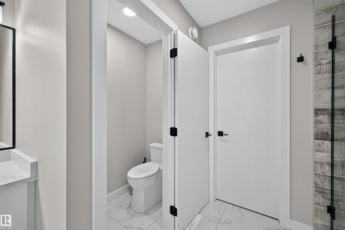 Modern bathroom featuring a toilet enclosure with marble-look tile flooring - 1573 Esaiw Place, Edmonton, AB 