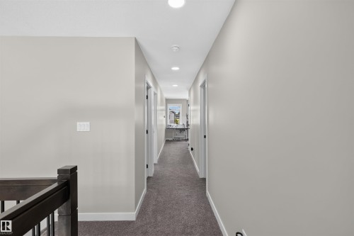 Hallway featuring recessed lighting, light gray painted walls, white trim, and dark gray carpet flooring - 1573 Esaiw Place, Edmonton, AB 