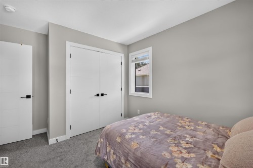 Neutral-toned room featuring a single window, white trim, gray carpet, and two white doors with black hardware - 1573 Esaiw Place, Edmonton, AB 