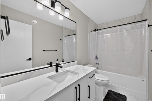 Modern bathroom featuring a single vanity with integrated sink, a white countertop with subtle veining, and matte black hardware - 1573 Esaiw Place, Edmonton, AB 