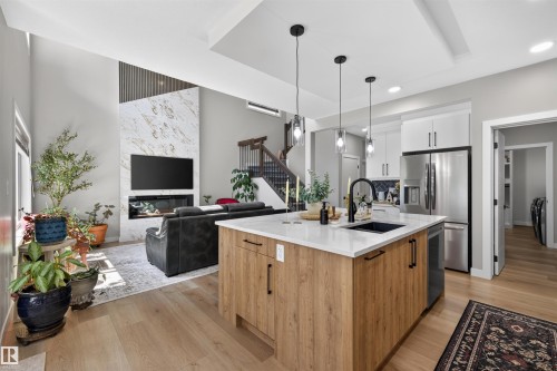 Open-concept living space featuring a central kitchen island with a dark sink, light countertops, and pendant lighting - 1573 Esaiw Place, Edmonton, AB 
