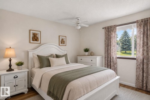 Bright bedroom featuring a large window, wood-finish flooring, and a ceiling fan - 13050 32A Street Nw, Edmonton, AB 