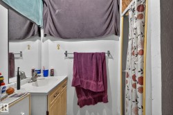 Bathroom featuring a single vanity with a laminate countertop, integrated sink, and wood-finish cabinetry - 