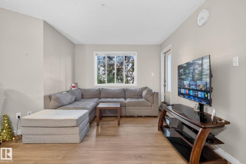 Hardwood-style flooring throughout a sunlit living space with light neutral wall tones - 140 301 Clareview Station Drive, Edmonton, AB 