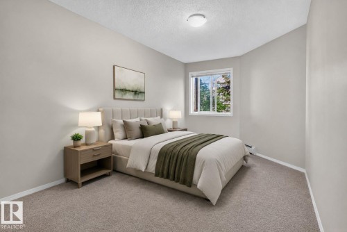 Bedroom featuring neutral wall paint, light brown carpeting, a window with exterior foliage, and a ceiling-mounted light fixture - 140 301 Clareview Station Drive, Edmonton, AB 