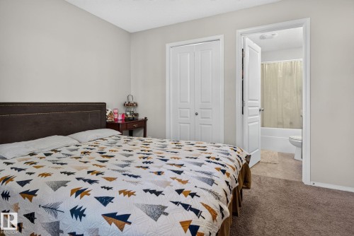 Bedroom featuring neutral wall colors, carpet flooring, a bifold closet, and an en-suite bathroom with a tub and shower combination - 140 301 Clareview Station Drive, Edmonton, AB 