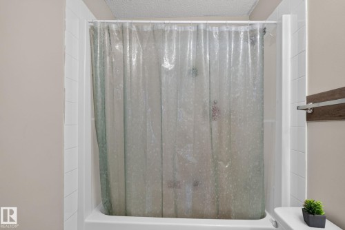 White porcelain tub and shower combination with white subway tile surround - 140 301 Clareview Station Drive, Edmonton, AB 
