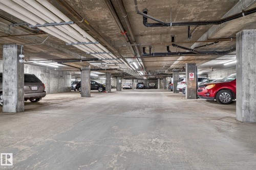 Underground parking facility with concrete construction, overhead piping, and fluorescent lighting - 140 301 Clareview Station Drive, Edmonton, AB 