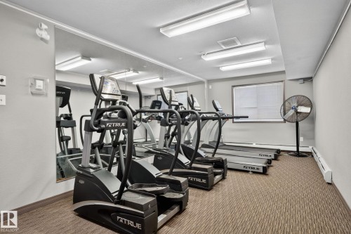 Dedicated fitness space featuring wall-mounted mirrors, recessed lighting, and textured carpeting - 140 301 Clareview Station Drive, Edmonton, AB 