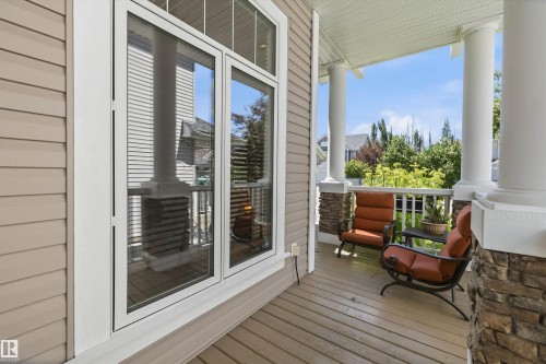 Covered porch featuring durable siding, large multi-pane windows, wood-finish flooring, white railing, and stone-accented columns - 533 Stewart Crescent, Edmonton, AB 