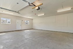 Spacious garage with concrete flooring, multiple fluorescent lighting fixtures, and two windows - 
