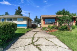 Property exterior featuring a front deck with wood railing, a large window with red shutters, and mature landscaping - 