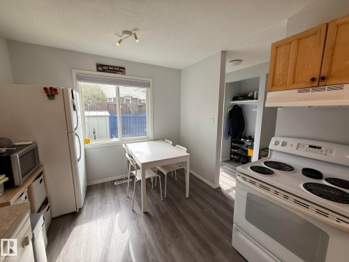 Kitchen featuring wood-finish flooring, light grey walls, a window with blinds, and recessed lighting - 166 Roseland Village, Edmonton, AB - Indoor Photo Showing Kitchen