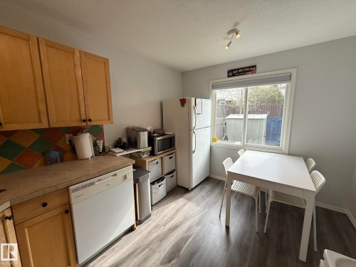 Kitchen featuring wood cabinetry, a colorful tile backsplash, and wood-finish flooring - 166 Roseland Village, Edmonton, AB - Indoor Photo Showing Kitchen