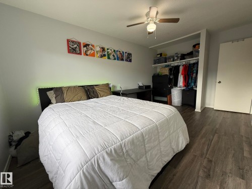 RPIMARY Bedroom featuring VINYL PLANK FLOORING, a ceiling fan with integrated lighting, and an open closet system with shelving and hanging storage - 166 Roseland Village, Edmonton, AB - Indoor Photo Showing Bedroom