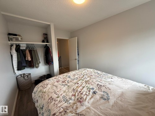 Another photo of the 2nd Upper Floor Bedroom that has an Open closet with shelving and hanging rod, light gray walls, and wood-finish flooring - 166 Roseland Village, Edmonton, AB - Indoor Photo Showing Bedroom