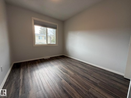 Another photo of the upper floor 3rd Bedroom featuring dark VINYL PLANK flooring, light grey walls, white baseboards, and a white window frame - 166 Roseland Village, Edmonton, AB - Indoor Photo Showing Other Room