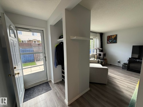 Inviting entry featuring a storm door, built-in coat closet, and wood-finish flooring extending into the main living area - 166 Roseland Village, Edmonton, AB - Indoor