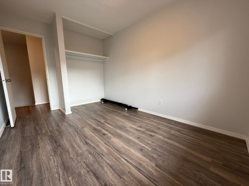 Interior room featuring wood-finish flooring, light neutral wall paint, and white baseboards - 166 Roseland Village, Edmonton, AB - Indoor Photo Showing Other Room