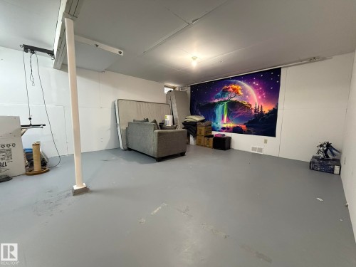 Unfinished basement featuring painted concrete flooring, white walls, and exposed ceiling joists - 166 Roseland Village, Edmonton, AB - Indoor