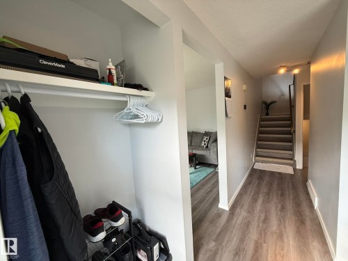Hallway featuring wood-finish flooring, light gray wall paint, and a staircase with matching risers - 166 Roseland Village, Edmonton, AB - Indoor Photo Showing Other Room