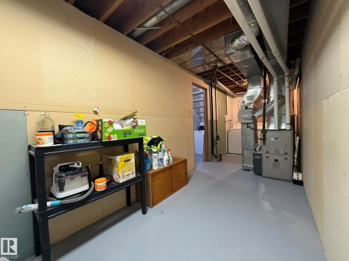 Utility area with painted concrete flooring, exposed ceiling joists, and visible ductwork - 166 Roseland Village, Edmonton, AB - Indoor Photo Showing Basement