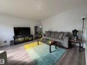 Spacious living area featuring light-toned walls and wood-finish flooring - 166 Roseland Village, Edmonton, AB  - Indoor Photo Showing Living Room 