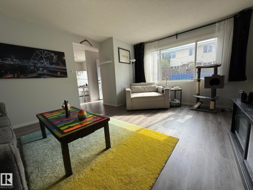 Living area with light-toned wall paint and wood-finish flooring - 166 Roseland Village, Edmonton, AB - Indoor Photo Showing Living Room