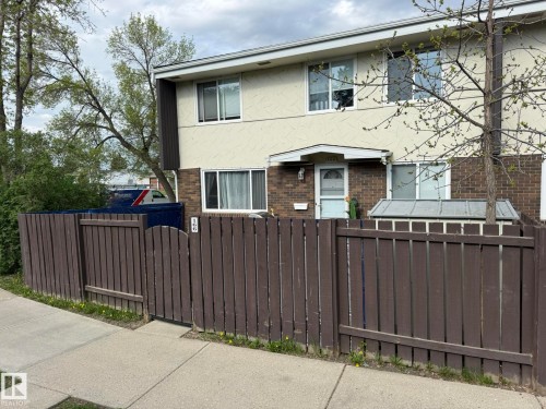 Two-story exterior featuring a brown picket fence and a concrete sidewalk - 166 Roseland Village, Edmonton, AB - Outdoor