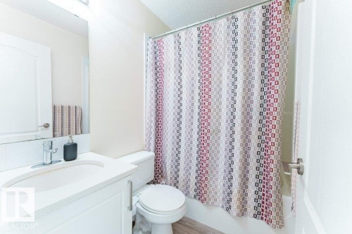 Bathroom featuring a white vanity with an integrated sink, chrome faucet, toilet, and a shower/tub combination - 3525 22 Street, Edmonton, AB - Indoor Photo Showing Bathroom