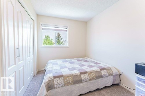 Bedroom featuring neutral-toned carpet, a white framed window with roller shade, and bi-fold closet doors - 3525 22 Street, Edmonton, AB - Indoor Photo Showing Bedroom