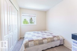 Bedroom featuring neutral-toned carpet, a white framed window with roller shade, and bi-fold closet doors - 
