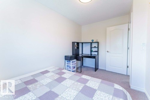 Neutral-toned carpeting extends throughout this room, featuring a white paneled door with brushed nickel hardware - 3525 22 Street, Edmonton, AB - Indoor Photo Showing Bedroom